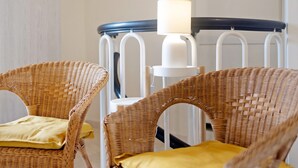 Wicker chairs with yellow cushions, a white lamp, and a blue railing.