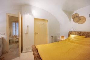 Ein Schlafzimmer mit Bett, Tür, Heizkörper und einer Wandleuchte.