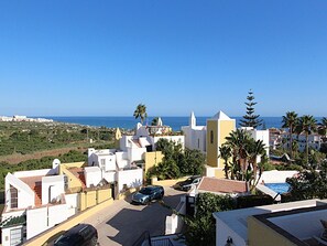 Un quartier résidentiel situé sur la côte, avec des bâtiments blancs, un ciel bleu azur et une vue sur la mer.