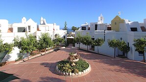 Ein Innenhof mit weißen Gebäuden, einem zentralen Garten und wolkenlosem, blauem Himmel.