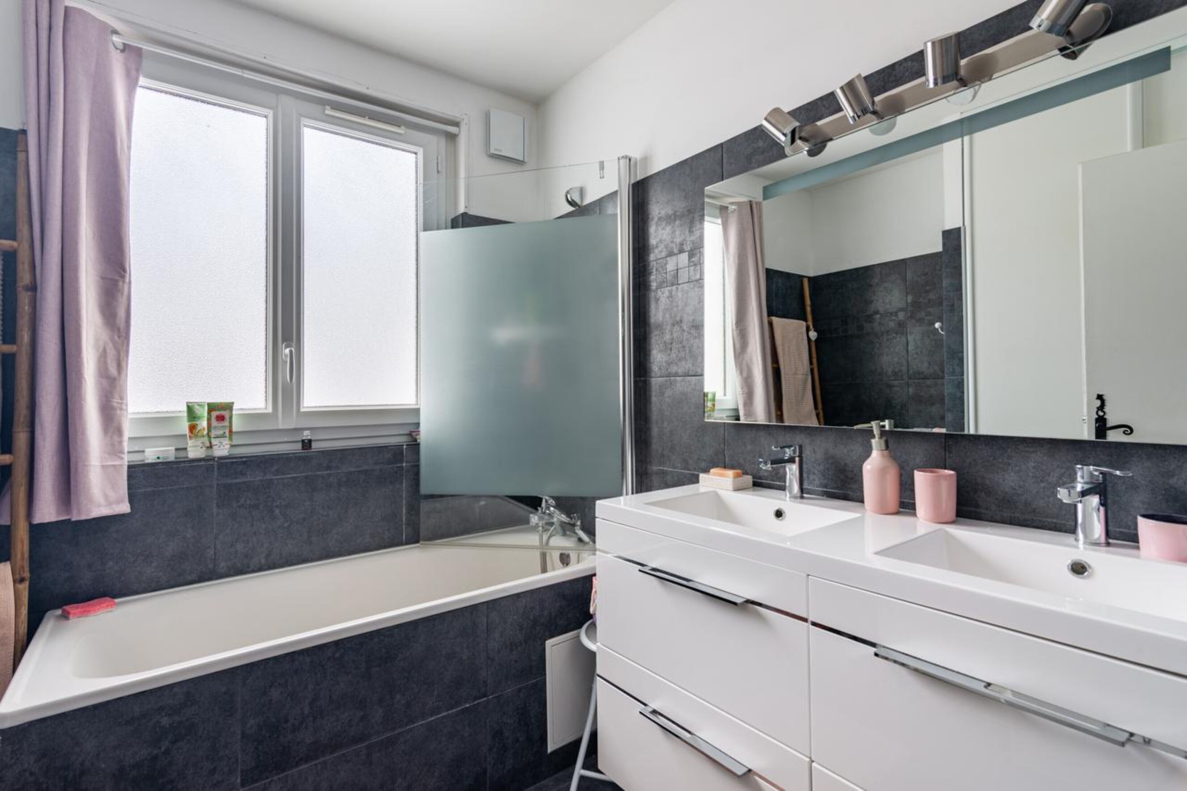 Une salle de bain moderne avec une baignoire, deux lavabos et un grand miroir.