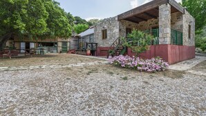 A stone building with a covered patio and a small garden with pink flowers.