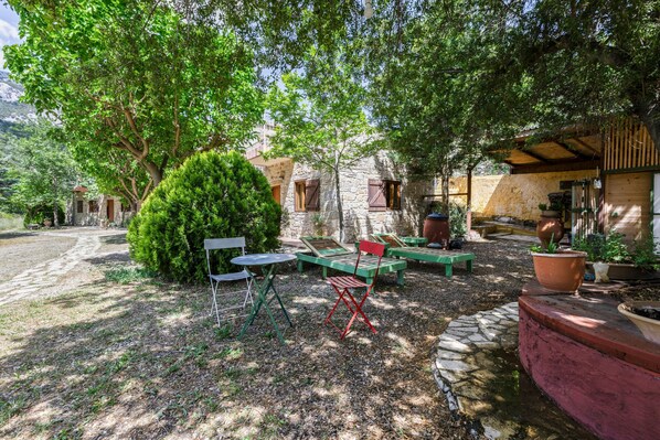 A rustic outdoor seating area with stone walls, wooden furniture, and potted plants.