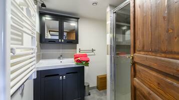 Une salle de bain avec un lavabo, un miroir, un porte-serviettes et une porte en bois.