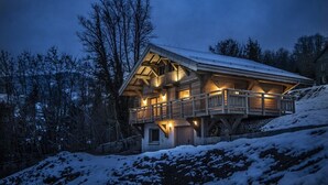 Ein Chalet mit Balkon, Holzfassade und verschneiter Umgebung.
