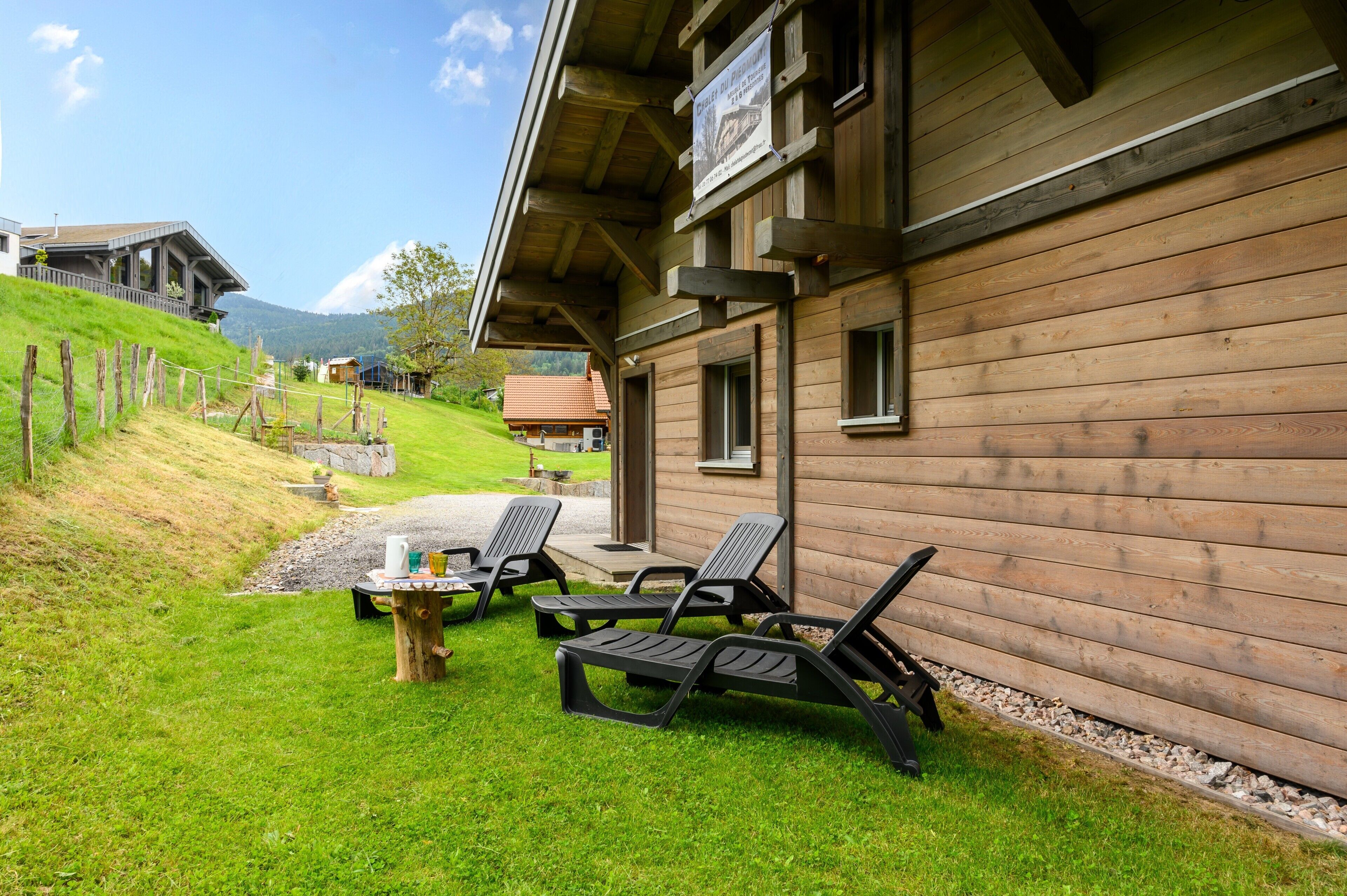 Un bâtiment en bois doté d’un patio couvert, d’un espace extérieur aménagé pour s’asseoir et offrant une vue sur une colline.