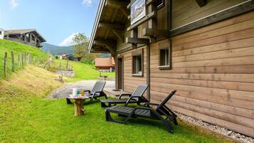Un bâtiment en bois doté d’un patio couvert, d’un espace extérieur aménagé pour s’asseoir et offrant une vue sur une colline.