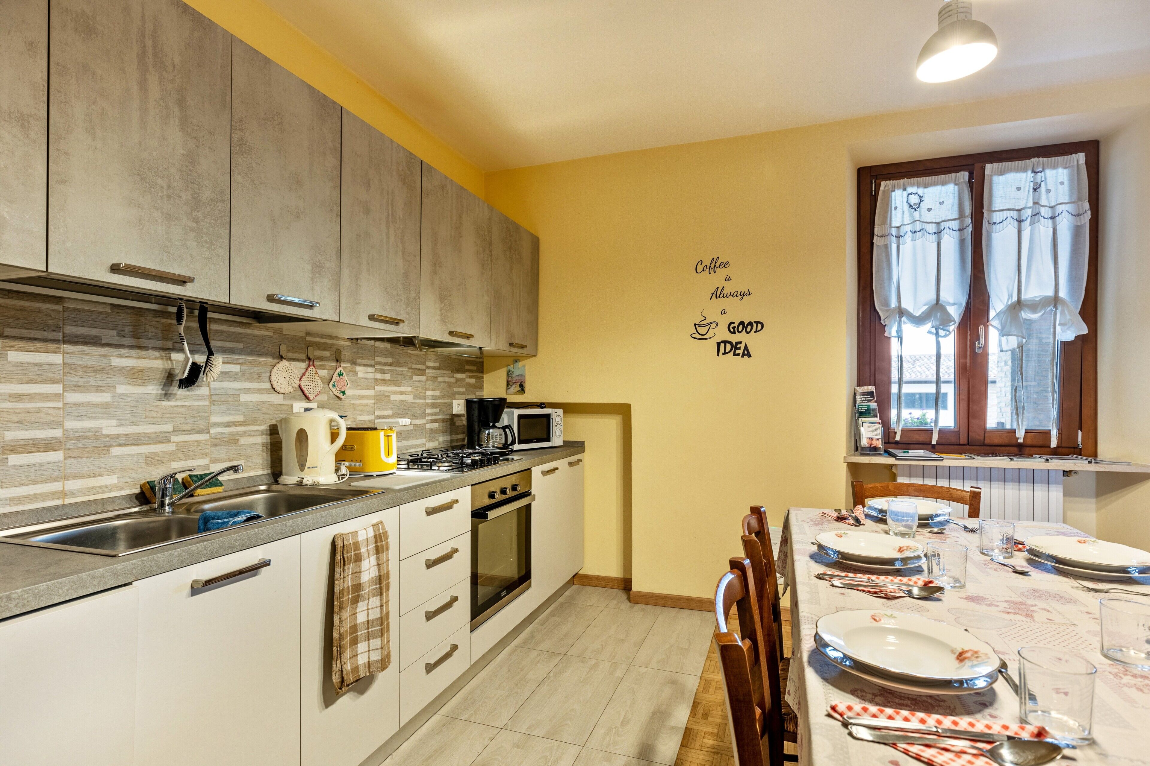 A kitchen with modern appliances, a dining table set for four, and a wall with a coffee-themed message.