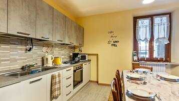 A kitchen with modern appliances, a dining table set for four, and a wall with a coffee-themed message.