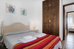 A bedroom with a bed, a nightstand, a lamp, two wall art pieces, and a wooden wardrobe. - Apartment 'Casa Miriam' with Balcony and Wi-Fi (Conil de la Frontera)