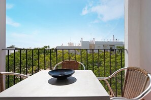 A balcony with a table and chairs, a bowl on the table, and a view of buildings and trees. - Apartment 'Casa Miriam' with Balcony and Wi-Fi (Conil de la Frontera)
