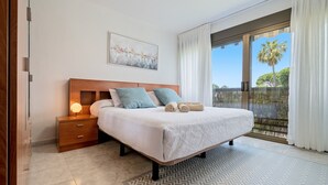 A bedroom with a bed, nightstand, and a view of the outdoors.