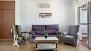 A living room with a sofa, two chairs, a coffee table, and a wall-mounted air conditioner. - Apartment 'Casa Mar' with Balcony, Wi-Fi and Air Conditioning (Conil de la Frontera)