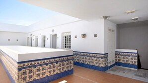 A room with a large bed, white walls, blue and yellow patterned tiles, and a tiled floor. - Apartment 'Casa Mar' with Balcony, Wi-Fi and Air Conditioning (Conil de la Frontera)