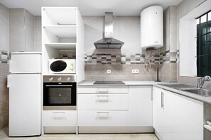 A modern kitchen with white cabinets, a built-in oven, a microwave, and a stainless steel sink.