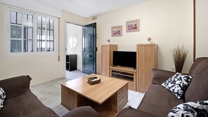 A living room with a sofa, a coffee table, a TV stand, and a door leading to another room. - Vacation Apartment "Dúplex Chanca" with Private Terrace (El Puerto de Sta María)