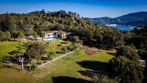 Une villa avec piscine, entourée d’une végétation luxuriante et de collines.