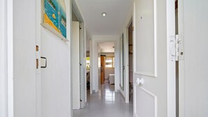 A hallway with white walls, a tiled floor, and doors leading to various rooms. - Holiday Apartment "Cambrils Park" with Sea View, Balcony & Shared Pool (Cambrils)