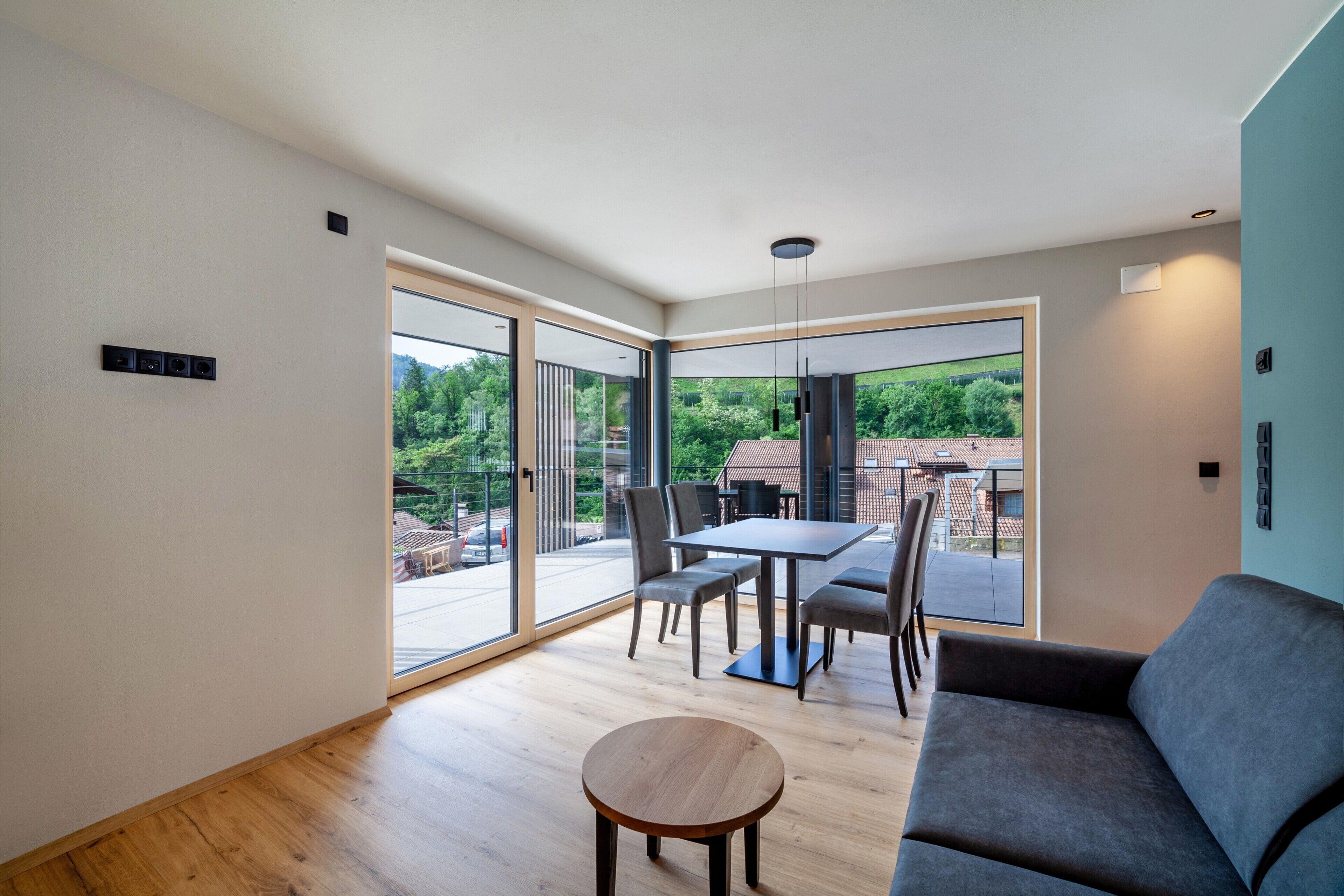 A modern living room with a sofa, a round table, and a dining area with chairs.