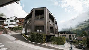 Un immeuble à plusieurs étages doté de balcons, d’un escalier et offrant une vue sur un paysage vallonné.
