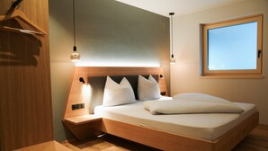 A modern bedroom with a wooden headboard, bedside tables, a window, and a hanging light fixture. - Apartment "Lodge Terrace Exclusive One" with Mountain View & Wi-Fi (Sankt Martin in Passeier)