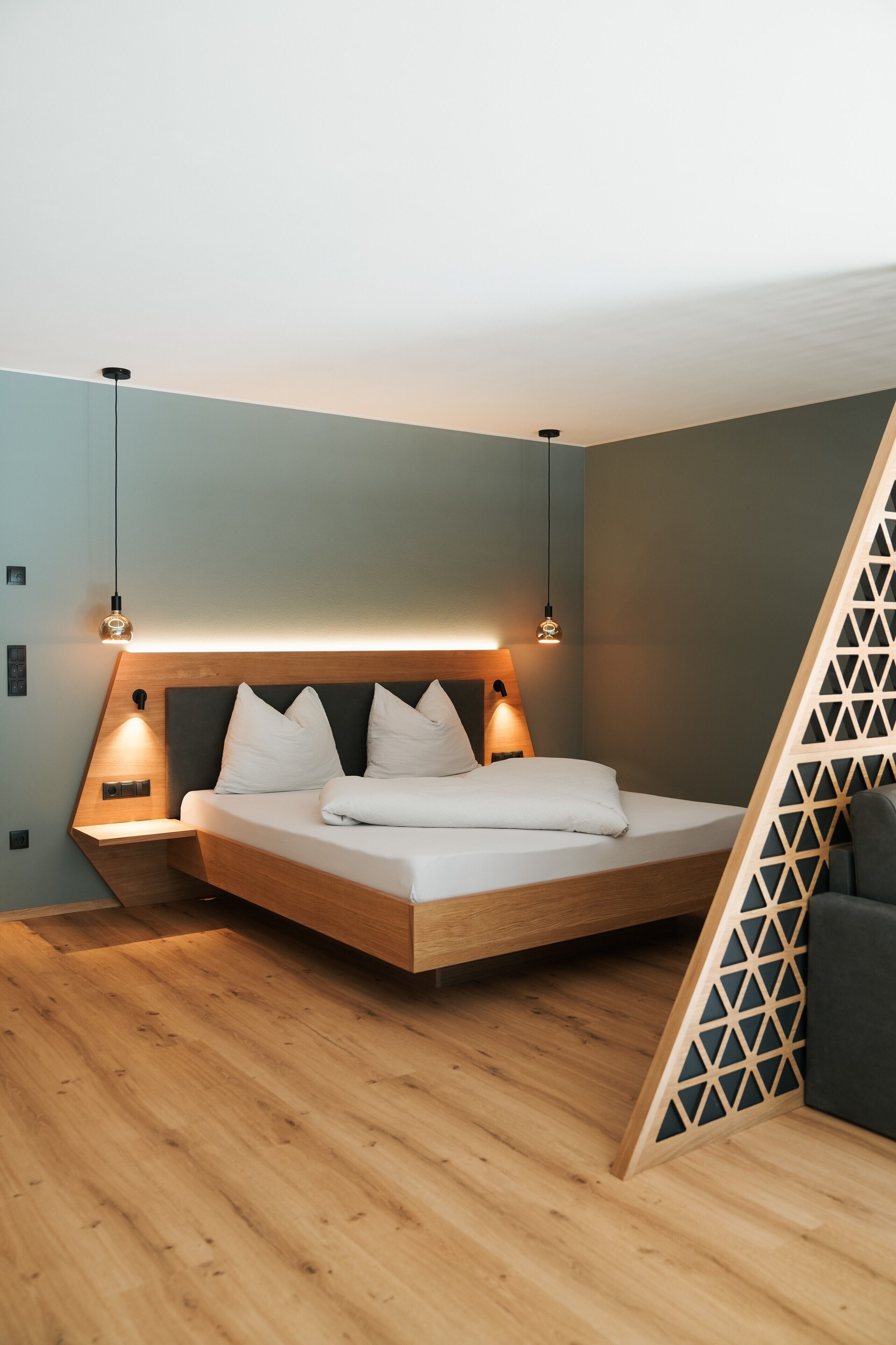 Une chambre moderne avec un lit en bois, deux lampes de chevet et un plafond en pente.