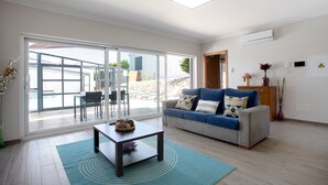 Una sala de estar moderna con sofá, mesa de centro y un amplio ventanal corredera que da a un espacio exterior.