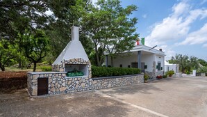 En stenbyggnad med en skorsten, märkt med texten ”Trullo Bello”, som ligger intill en vit byggnad med en flagga.
