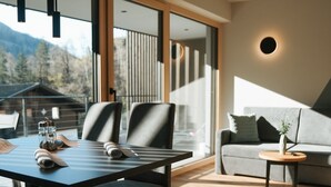 A modern living room with a dining area, large windows, and a view of the outdoors. - Apartment "Lodge Terrace Exclusive Large" with Mountain View & Wi-Fi (Sankt Martin in Passeier)