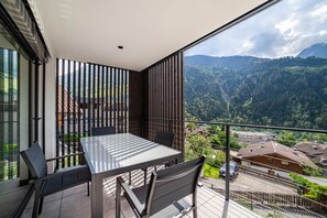 Un balcon avec une table et des chaises, offrant une vue sur un paysage montagneux.