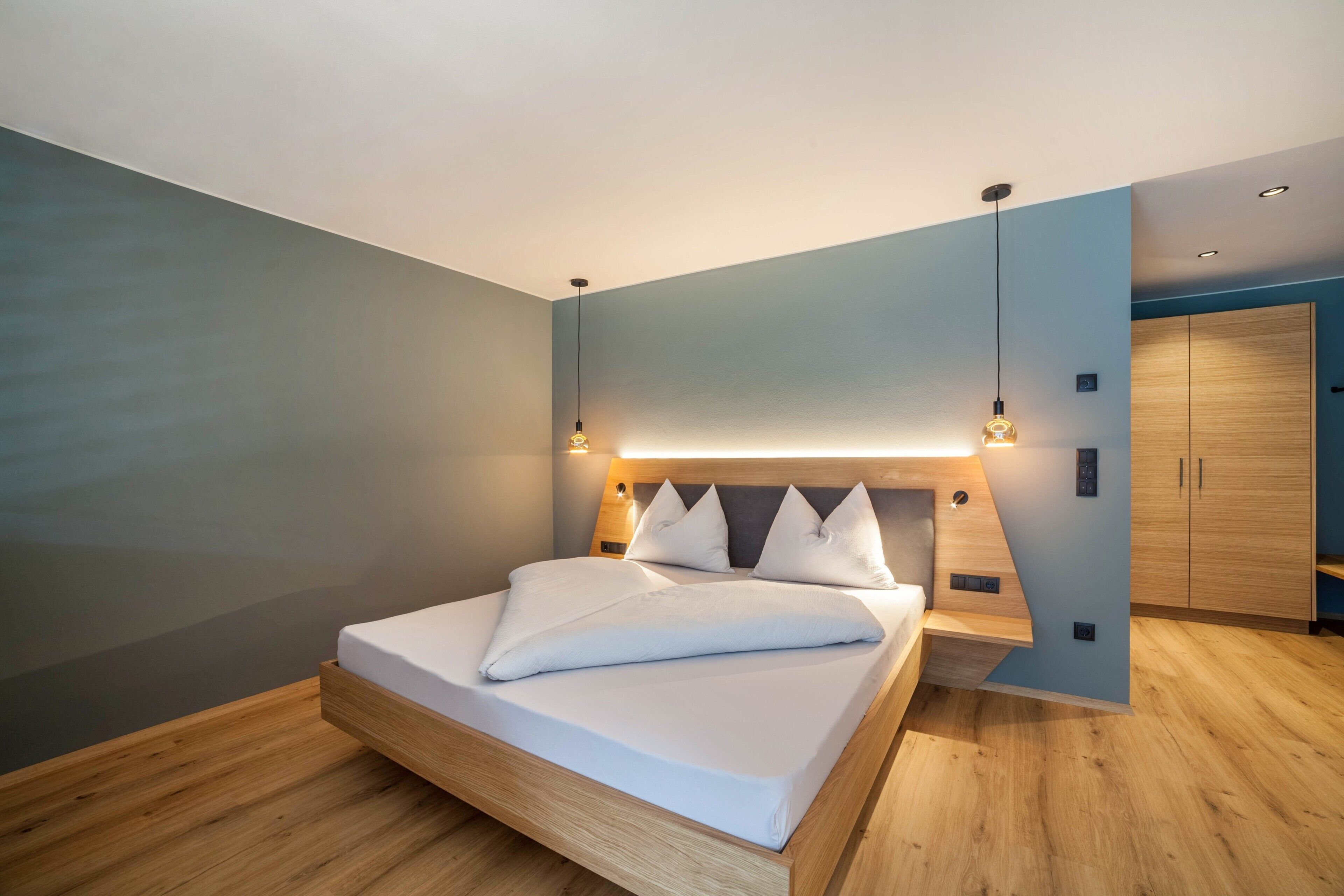 Um quarto moderno com cama de madeira, mesas de cabeceira embutidas e um guarda-roupa.