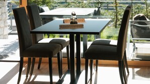 Zona pranzo moderna con tavolo e sedie, ampie finestre e vista sugli alberi.