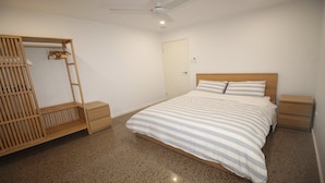 Un dormitorio con cama, armario de madera y ventilador de techo.