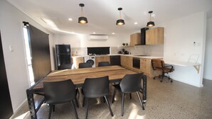 Una cocina moderna con una mesa de comedor de madera, sillas negras e iluminación colgante.
