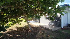 Una propiedad residencial con un porche cubierto, un garaje y un árbol en primer plano.