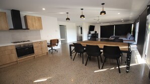 Una cocina moderna con una isla central, armarios de madera y una zona de comedor con sillas.