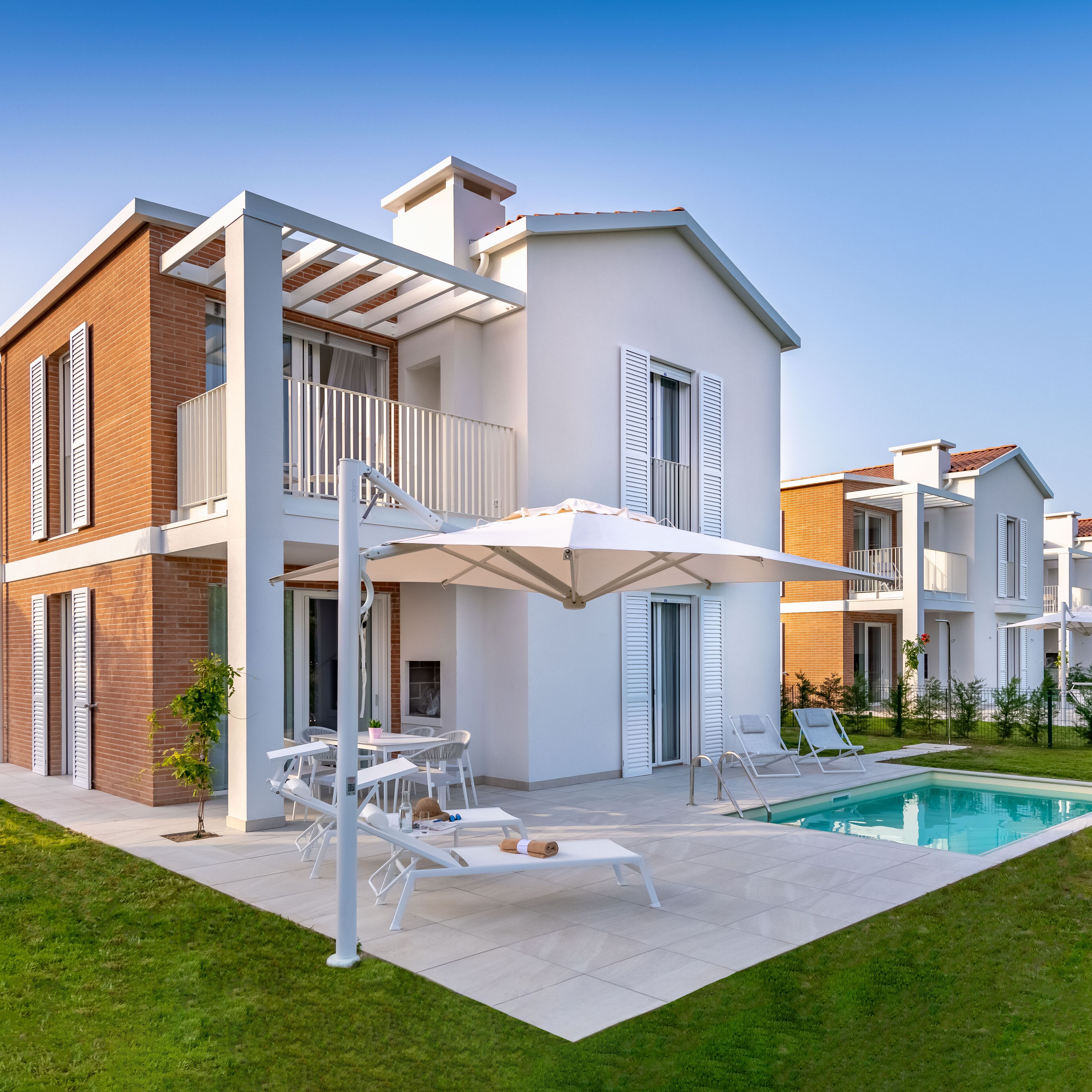 A modern two-story house with a swimming pool, outdoor seating, and a covered patio area.