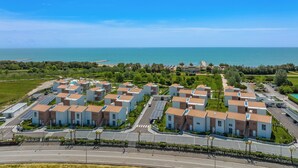 Una zona residencial costera con edificios modernos, una calle y una playa al fondo.