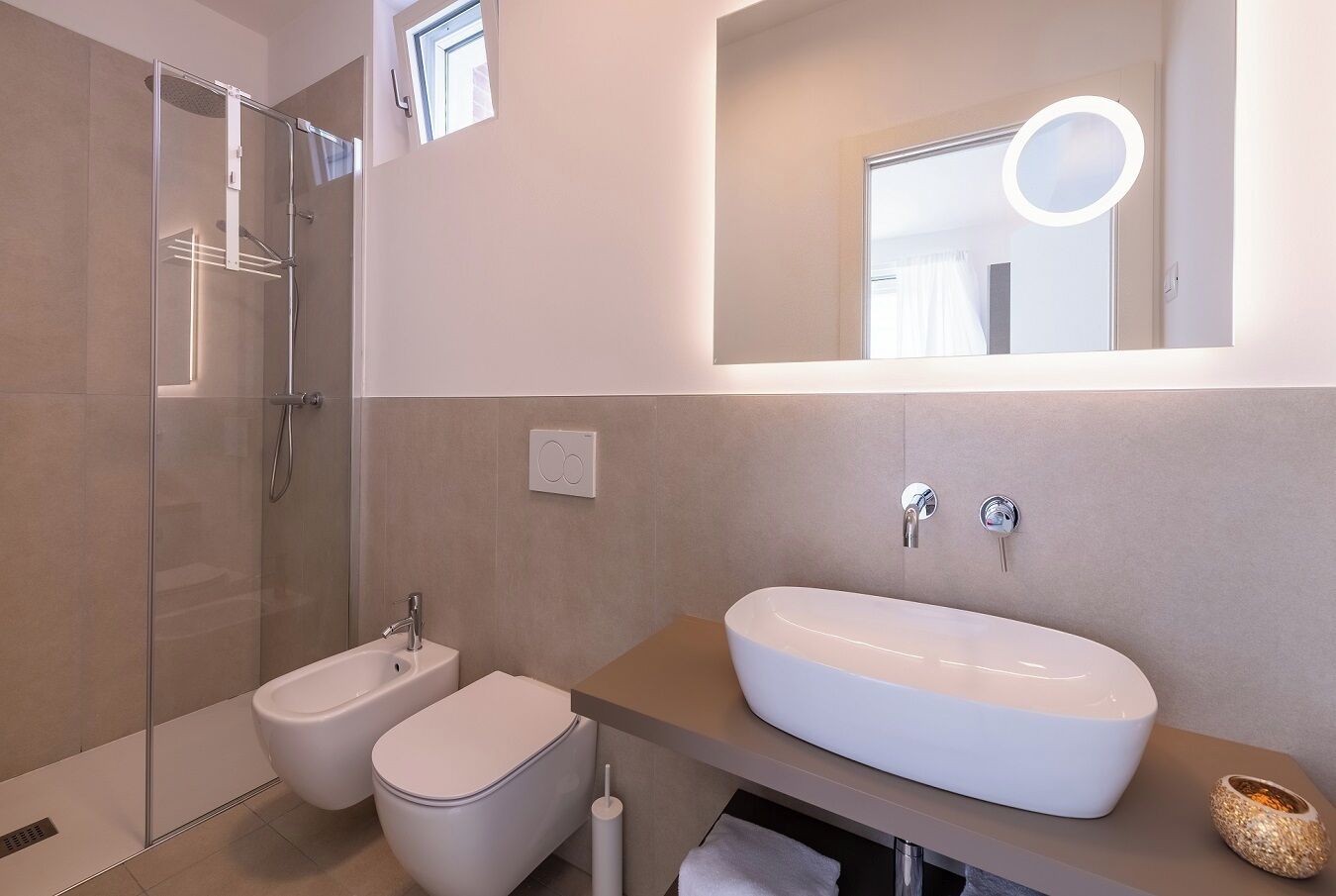A modern bathroom with a glass-enclosed shower, a white sink, and a bidet.