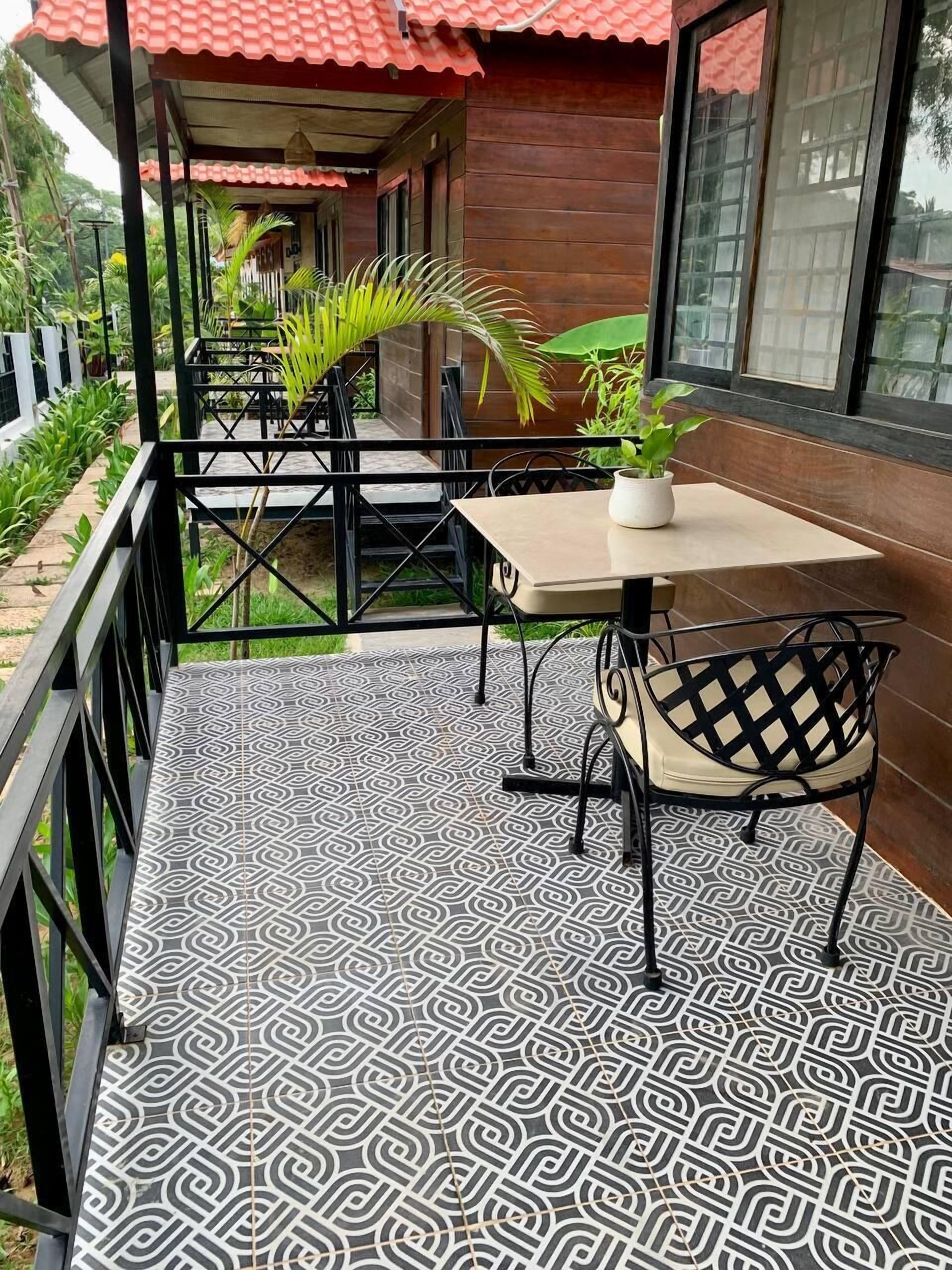 A covered outdoor seating area with patterned flooring, tables, and chairs.
