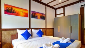 Una habitación de hotel con una cama grande, ropa de cama azul y blanca, dos cuadros en la pared y un armario.
