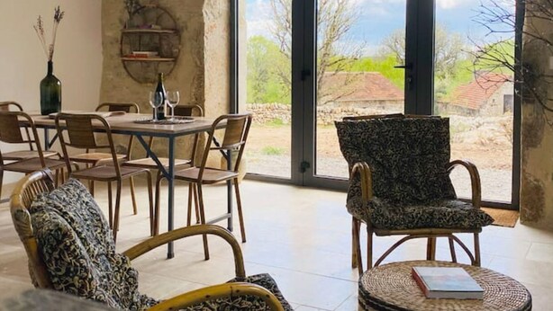 Un comedor con una mesa dispuesta para cuatro personas, rodeada de sillas de mimbre y un ventanal que ofrece vistas al exterior.
