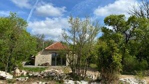 Un edificio de piedra con techo de tejas, rodeado de árboles y rocas.