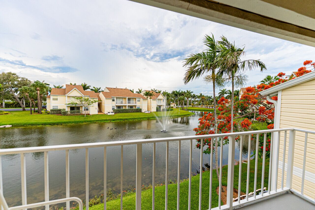 A residential area with a water feature, palm trees, and houses with a uniform architectural style.