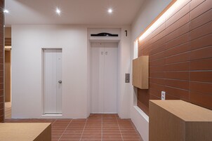 Un ascensor moderno con pantalla digital, una mesa de recepción y una pared con diseño de paneles de madera.