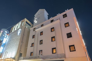 Un hotel de varios pisos con un diseño arquitectónico moderno, que destaca por una torre imponente y numerosas ventanas.