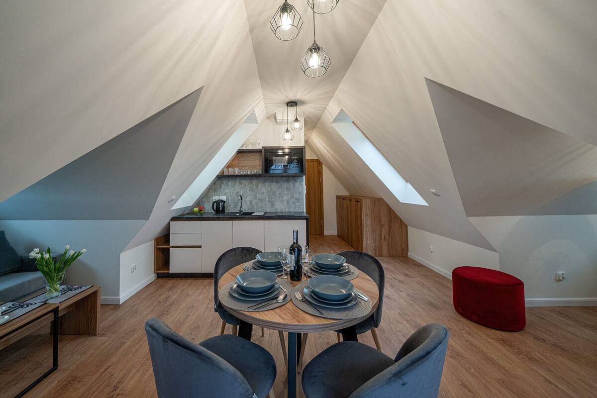 Um loft moderno com área de jantar, cozinha e um banquinho vermelho.