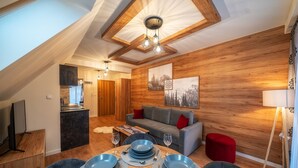 A dining area with a wooden ceiling, a sofa, and a red ottoman. - Sun & Snow Resorts G Białka Tatrzanska (Bukowina Tatrzanska)
