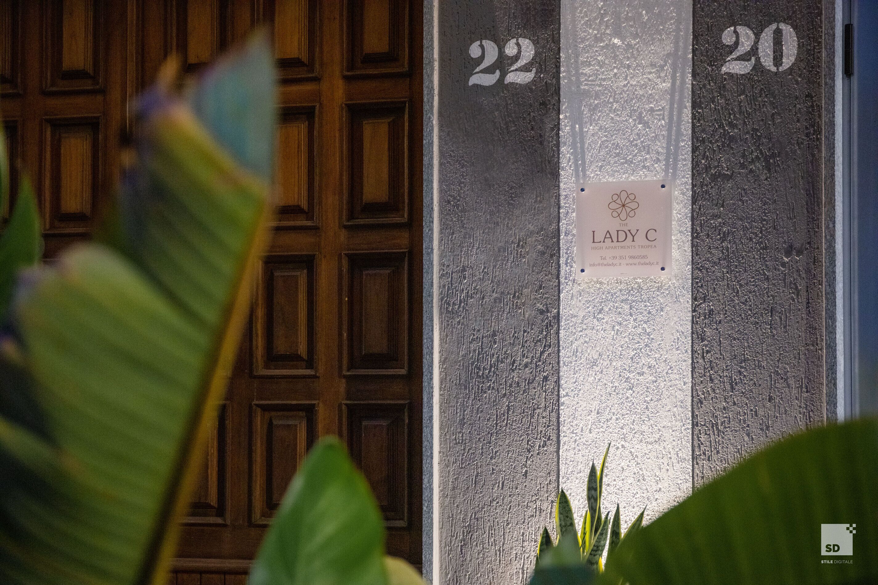 A door with the numbers 22 and 20, a sign for 'The Lady C' with contact information, and a logo for 'Style Digitale'.