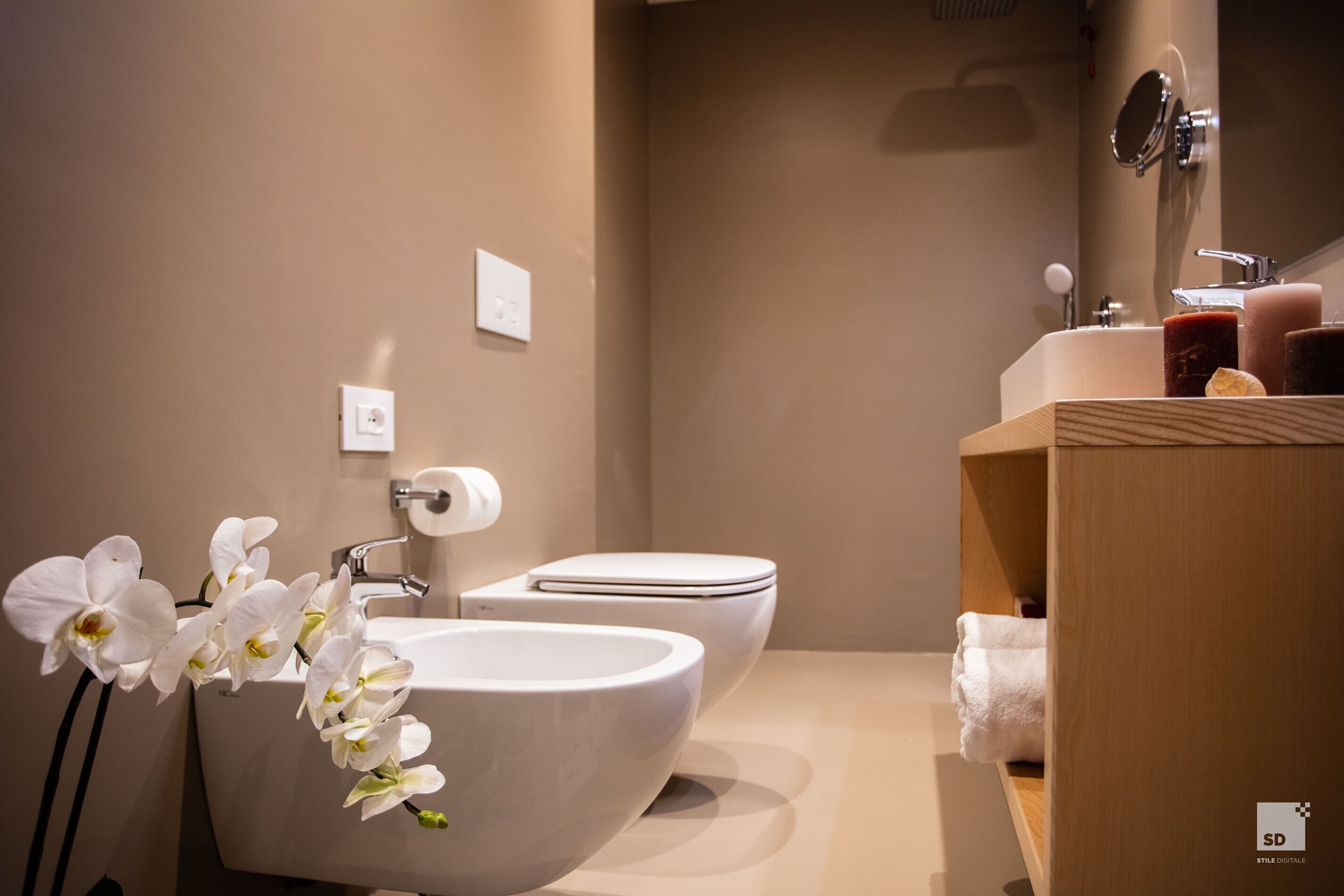 Une salle de bain moderne avec un lavabo blanc, des toilettes et un meuble-lavabo en bois.